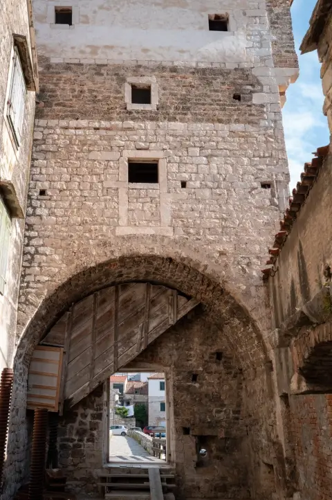 Vieux portail en bois sous une arche de pierre dans une ruelle, Trogir
