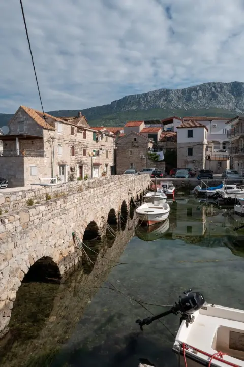 Petit pont de pierre enjambant le canal bordé de bateaux, Trogir