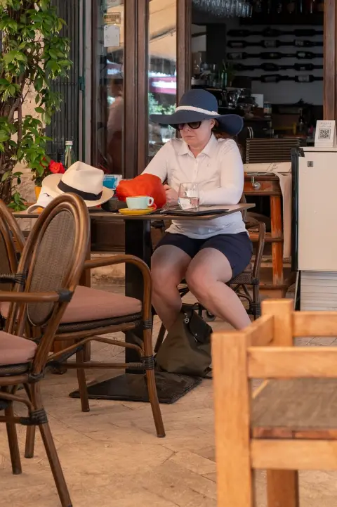 Une touriste au chapeau de paille attablée à la terrasse d'un café, Trogir