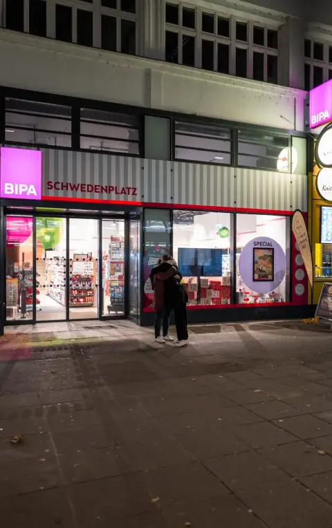 Couple s'enlacant devant la vitrine illuminee du magasin, Vienne