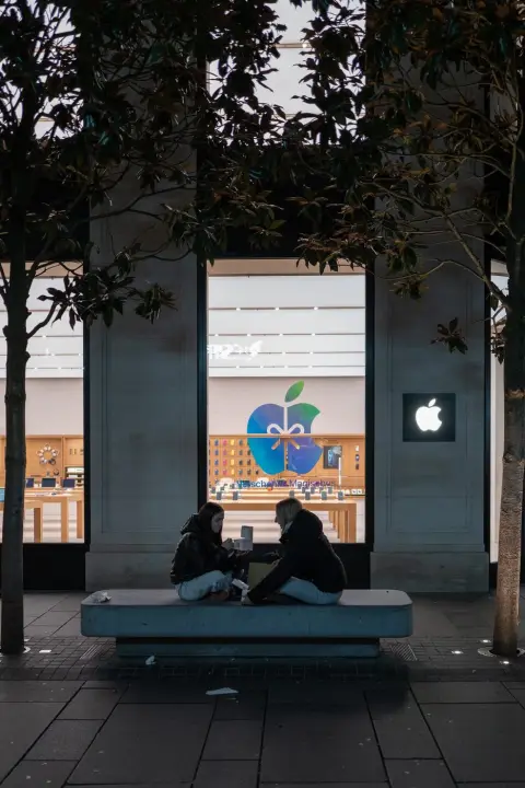 Deux amies assises sur un banc devant la vitrine Apple, Vienne