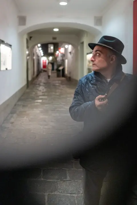 Homme au chapeau observant une ruelle voutee eclairee, Vienne