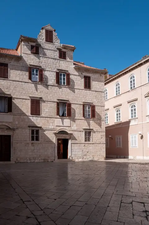 Façade Renaissance aux volets bruns dominant une place vide, Zadar