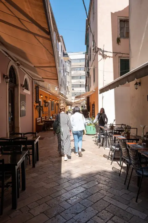Deux passantes marchant sous les auvents orangés d'une ruelle commerçante, Zadar