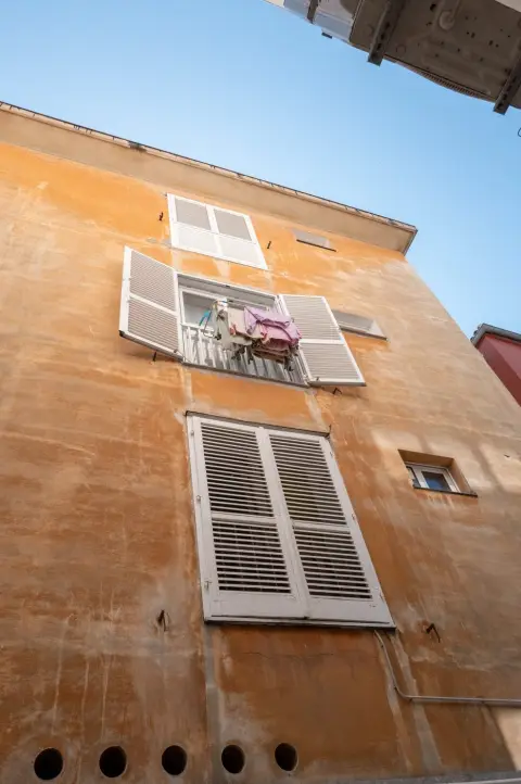 Linge séchant à la fenêtre d'une façade ocre aux volets blancs, Zadar