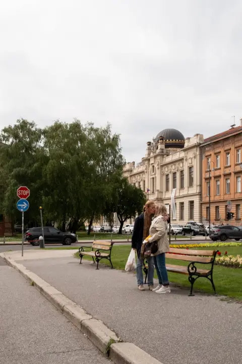 Un couple s'embrassant sur un banc face à un bâtiment à coupole, Zagreb