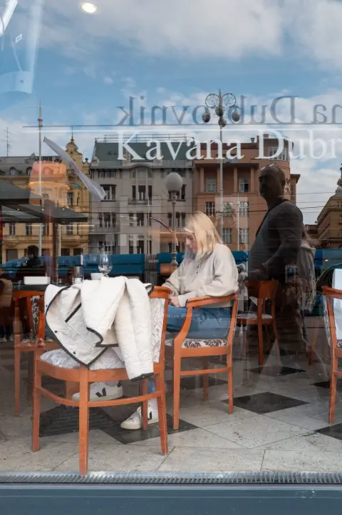 Reflet d'un café Kavana Dubrovnik dans une vitrine, silhouettes attablées, Zagreb