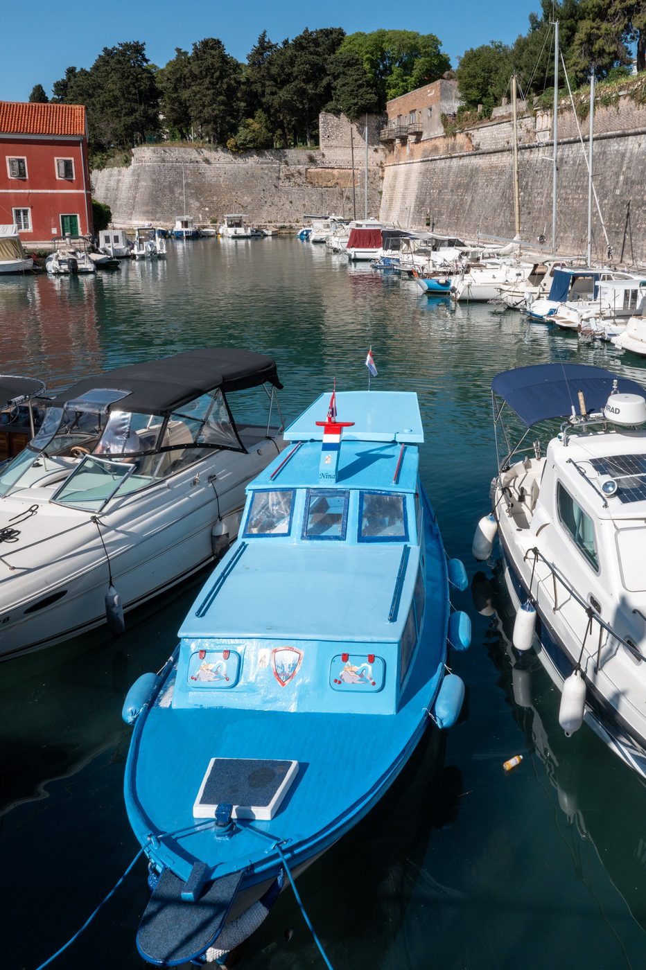 Small sky-blue boat moored facing the old town ramparts, Zadar