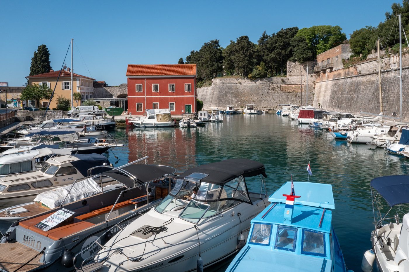 Marina lined with ancient ramparts and a house with red shutters, Zadar