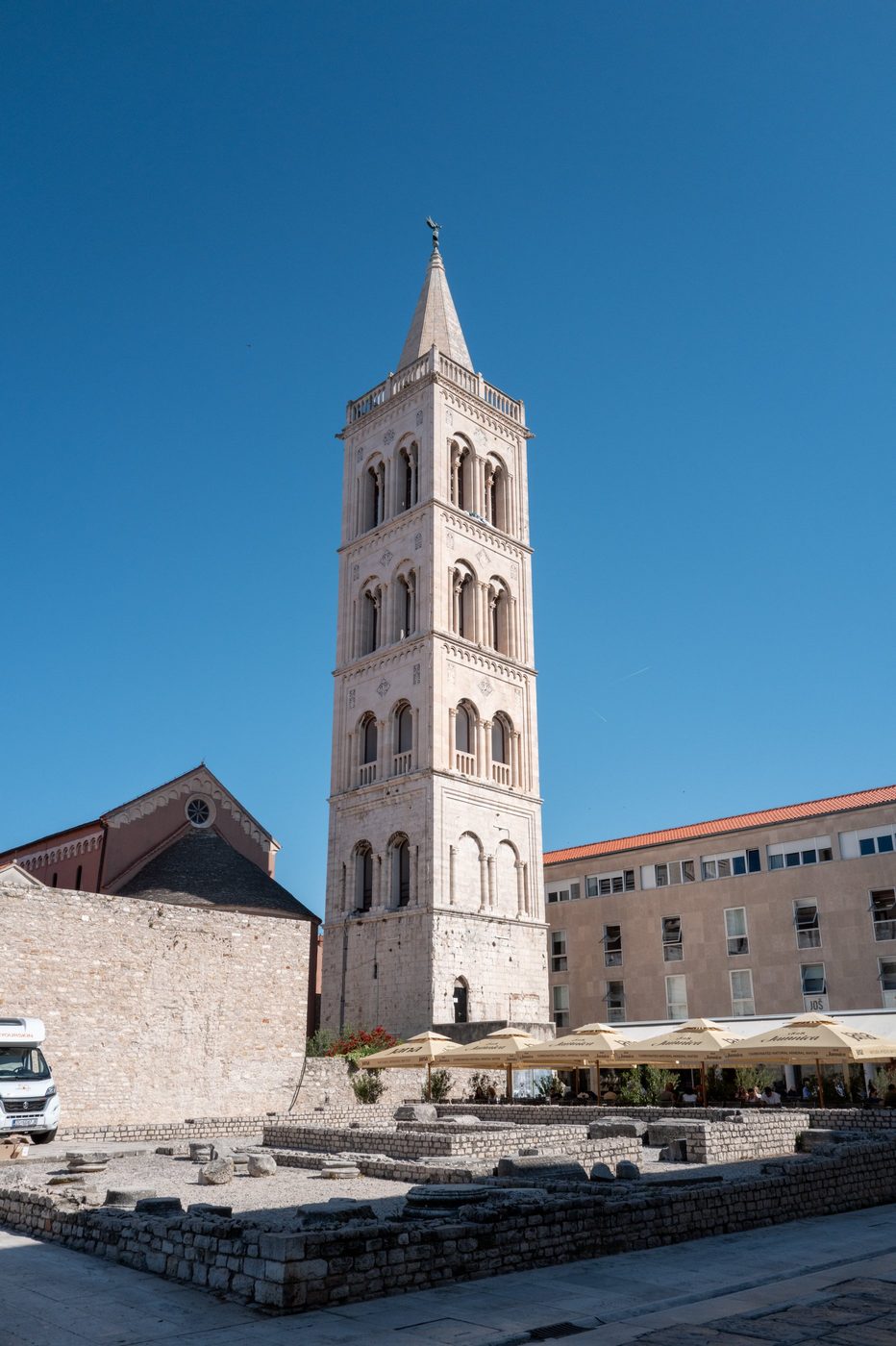 Slender cathedral bell tower rising above the restaurant terraces, Zadar