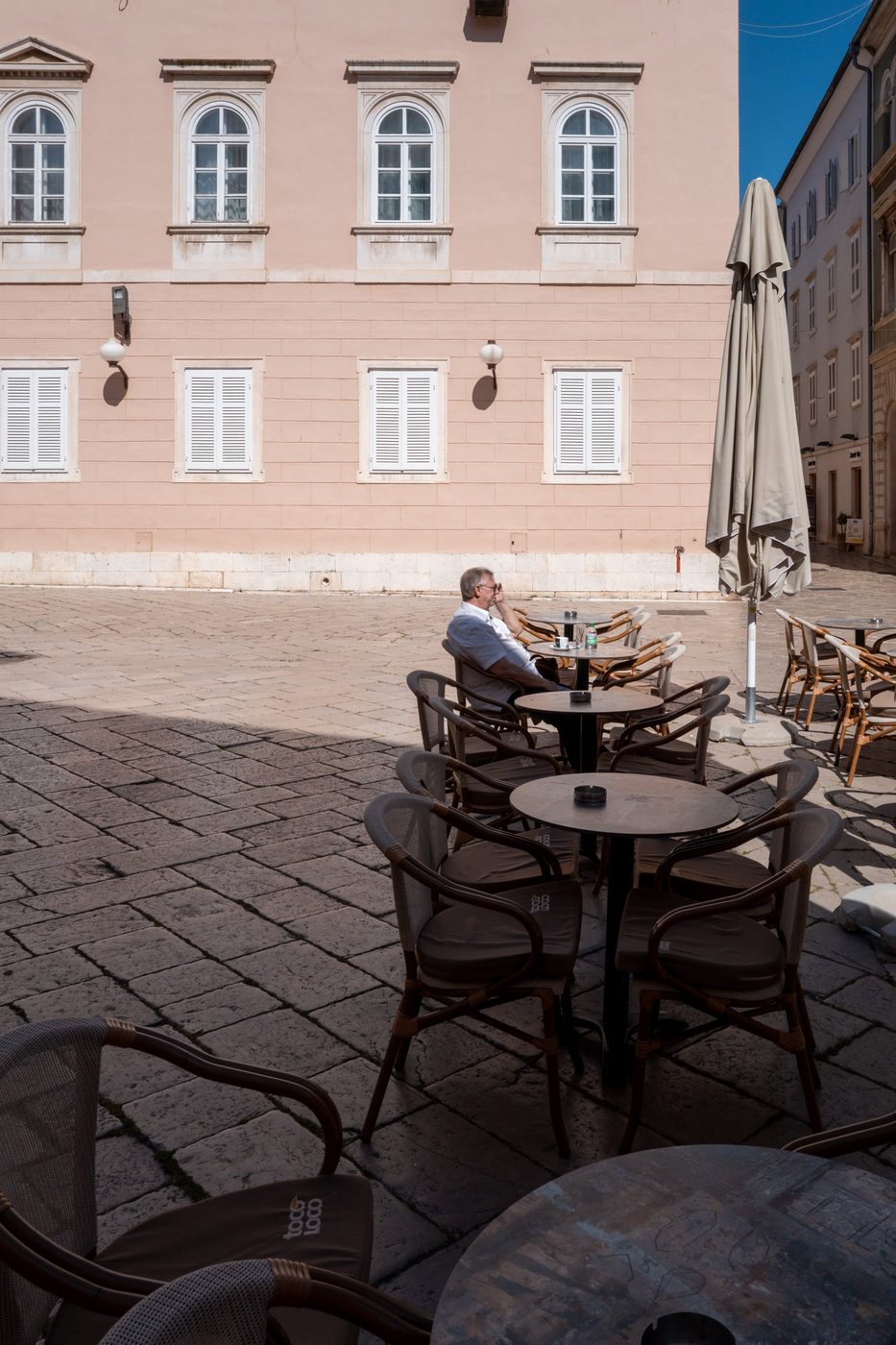 A man on the phone sitting alone at a café terrace, Zadar