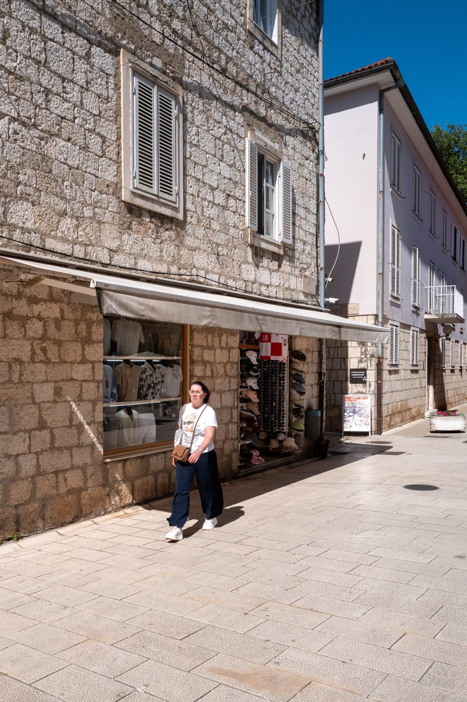 A passerby in front of a souvenir shop with a colorful display, Zadar