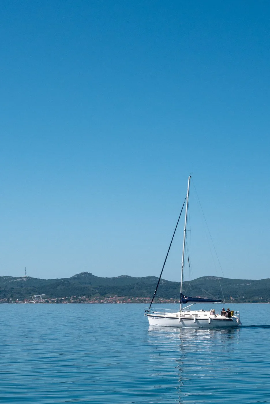 Voilier solitaire voguant sur une mer calme face à la côte, Zadar