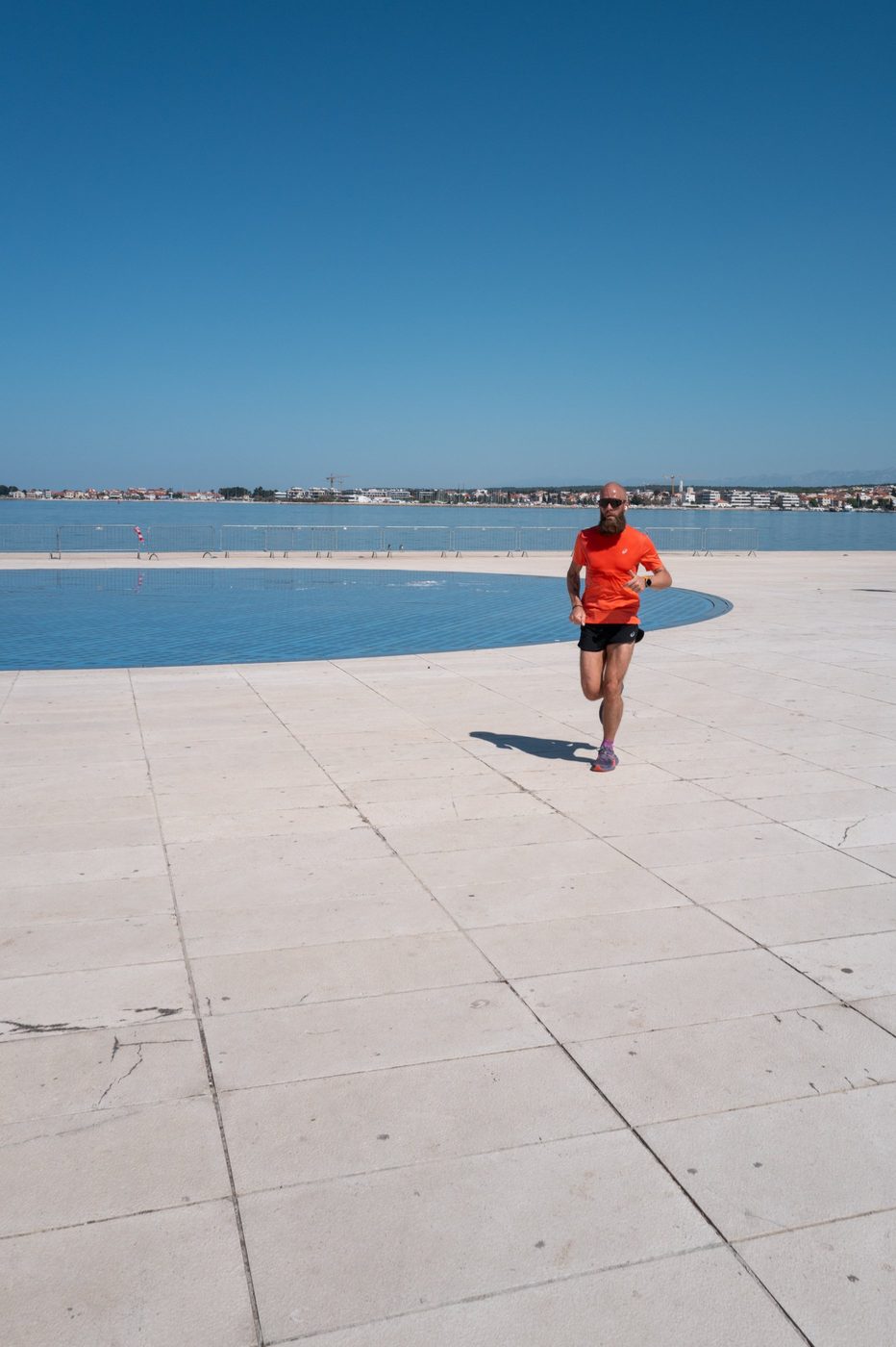 Bearded runner in orange gear along the waterfront basin, Zadar