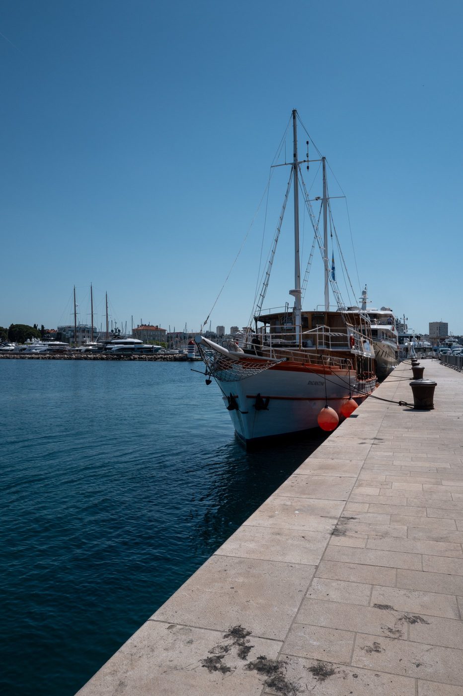 Wooden sailboat moored at the quay, marina in the background, Zadar