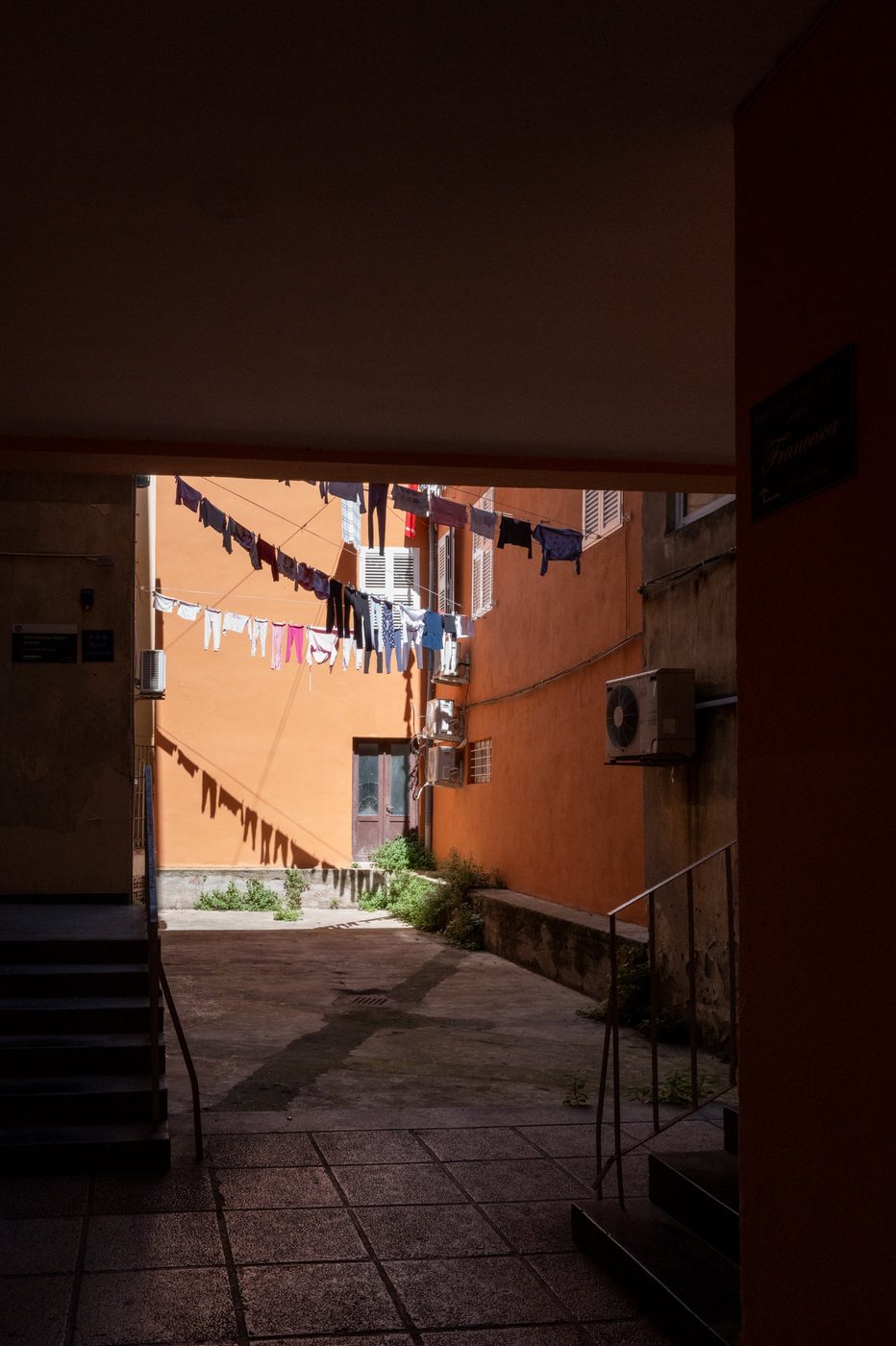 Laundry hung between two ochre façades in a shaded courtyard, Zadar