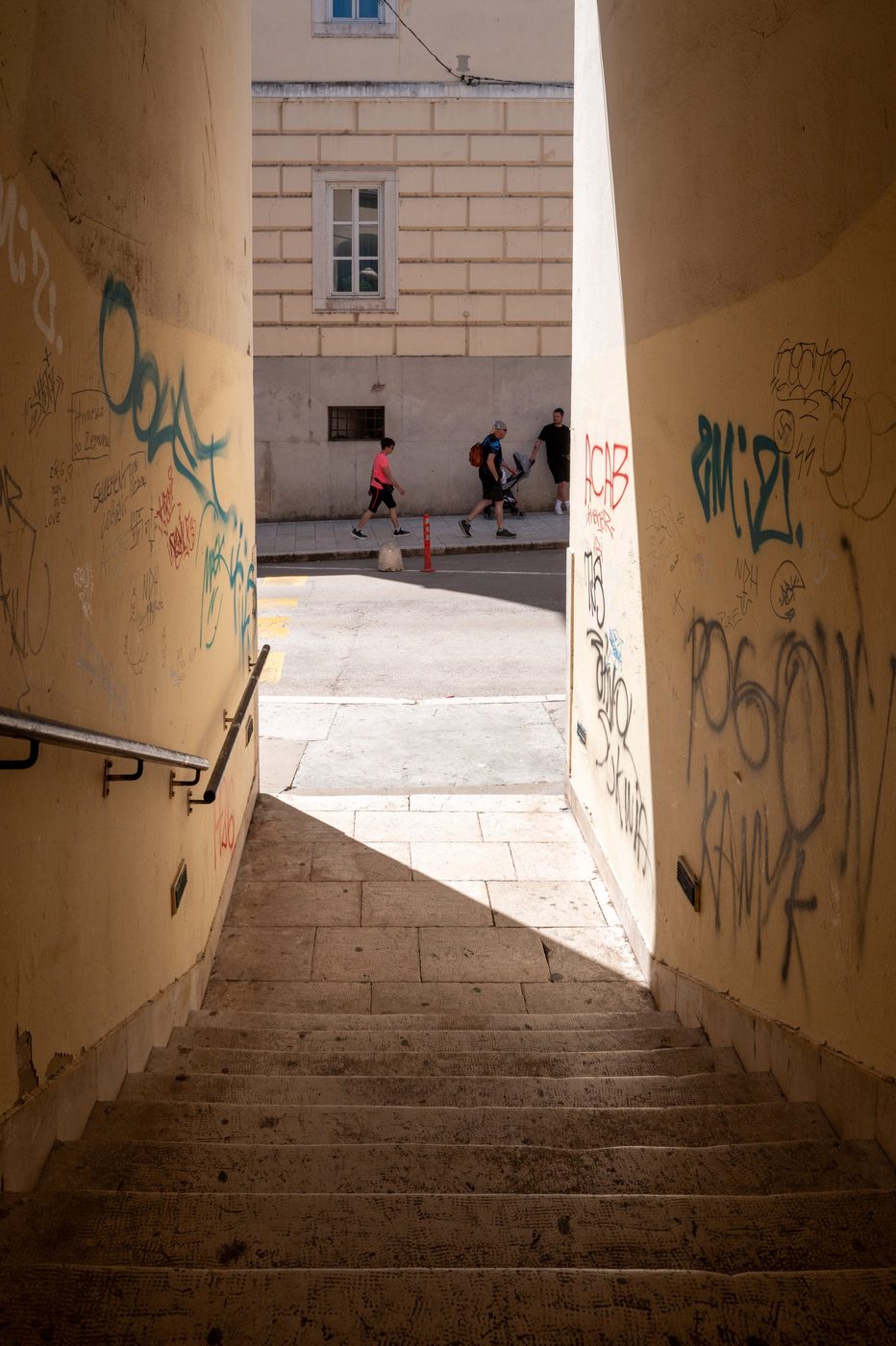 Graffiti-covered underground staircase opening onto a busy street, Zadar