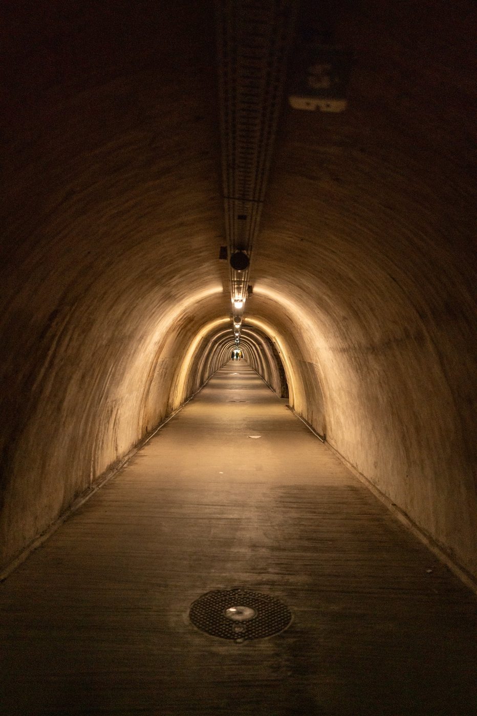 Perspective of the underground Grič tunnel with silhouettes in the distance, Zagreb