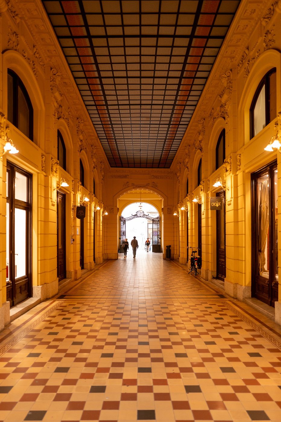 Yellow arcade leading to a wrought-iron gate, bicycle parked on the right, Zagreb