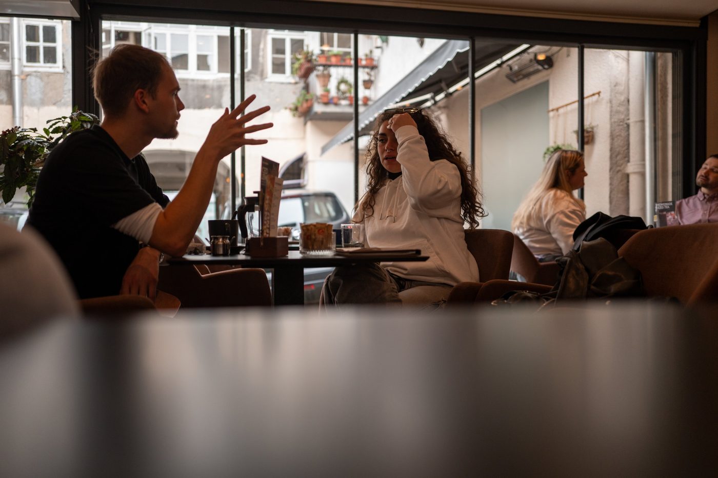 A man gesturing mid-conversation at a café terrace, Zagreb