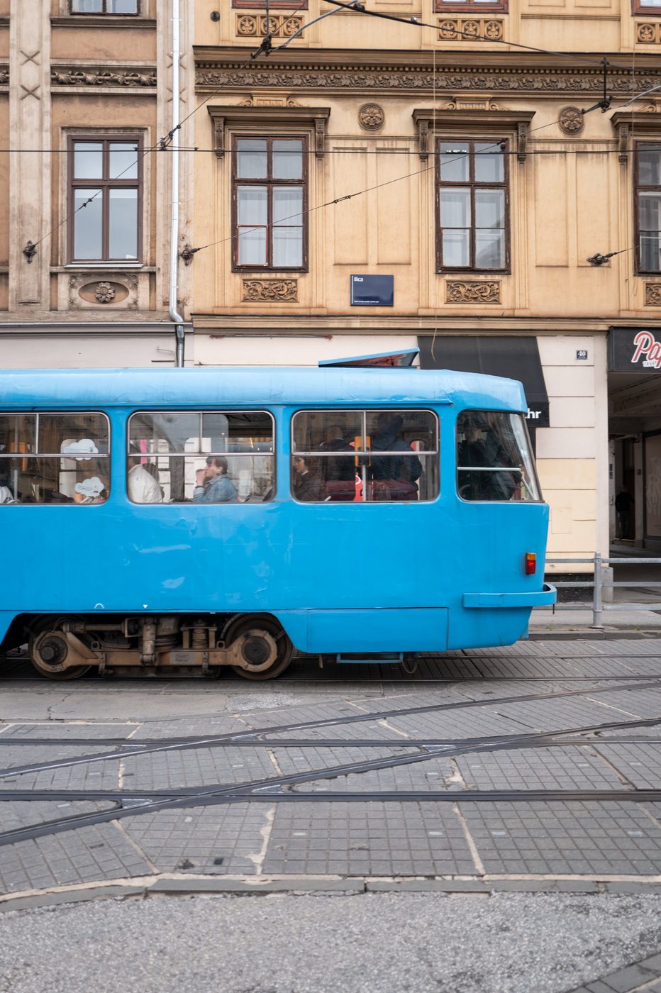 Old blue tram running past an ornate façade, Zagreb