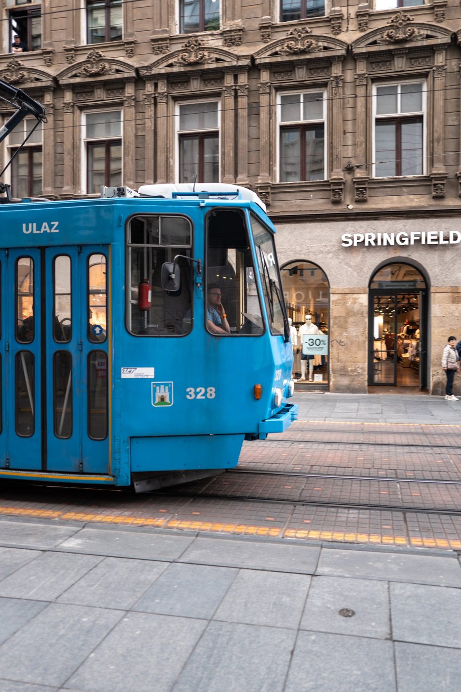 Blue tram number 328 with the driver at the wheel, Zagreb