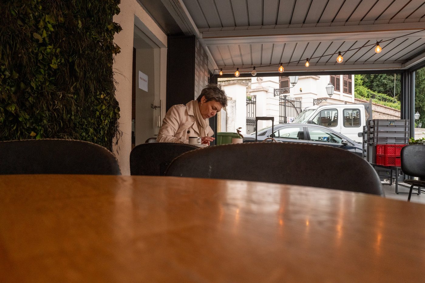 A woman sitting alone beneath a café pergola, Zagreb