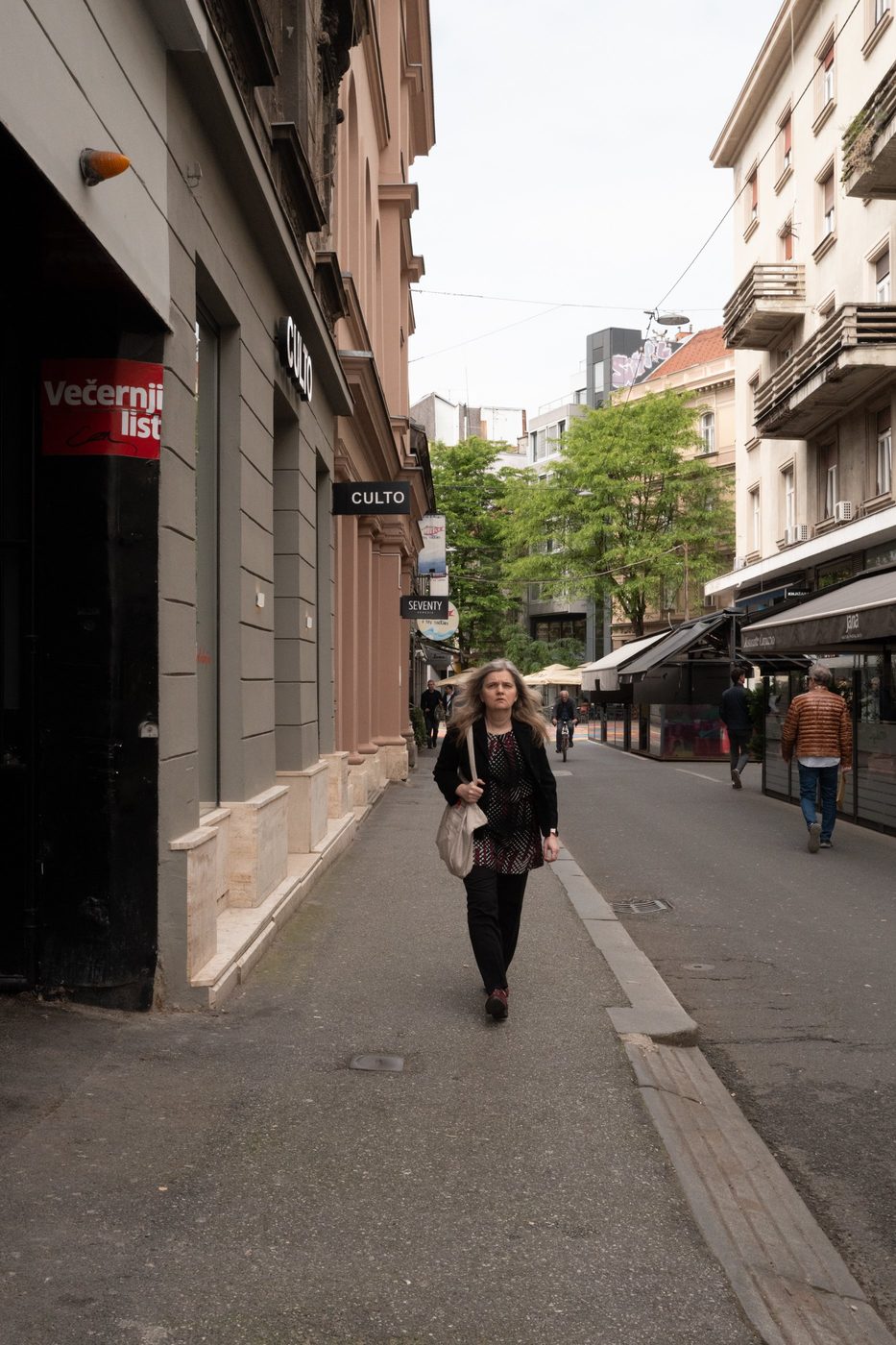 A passerby walking alone down a street lined with shops, Zagreb