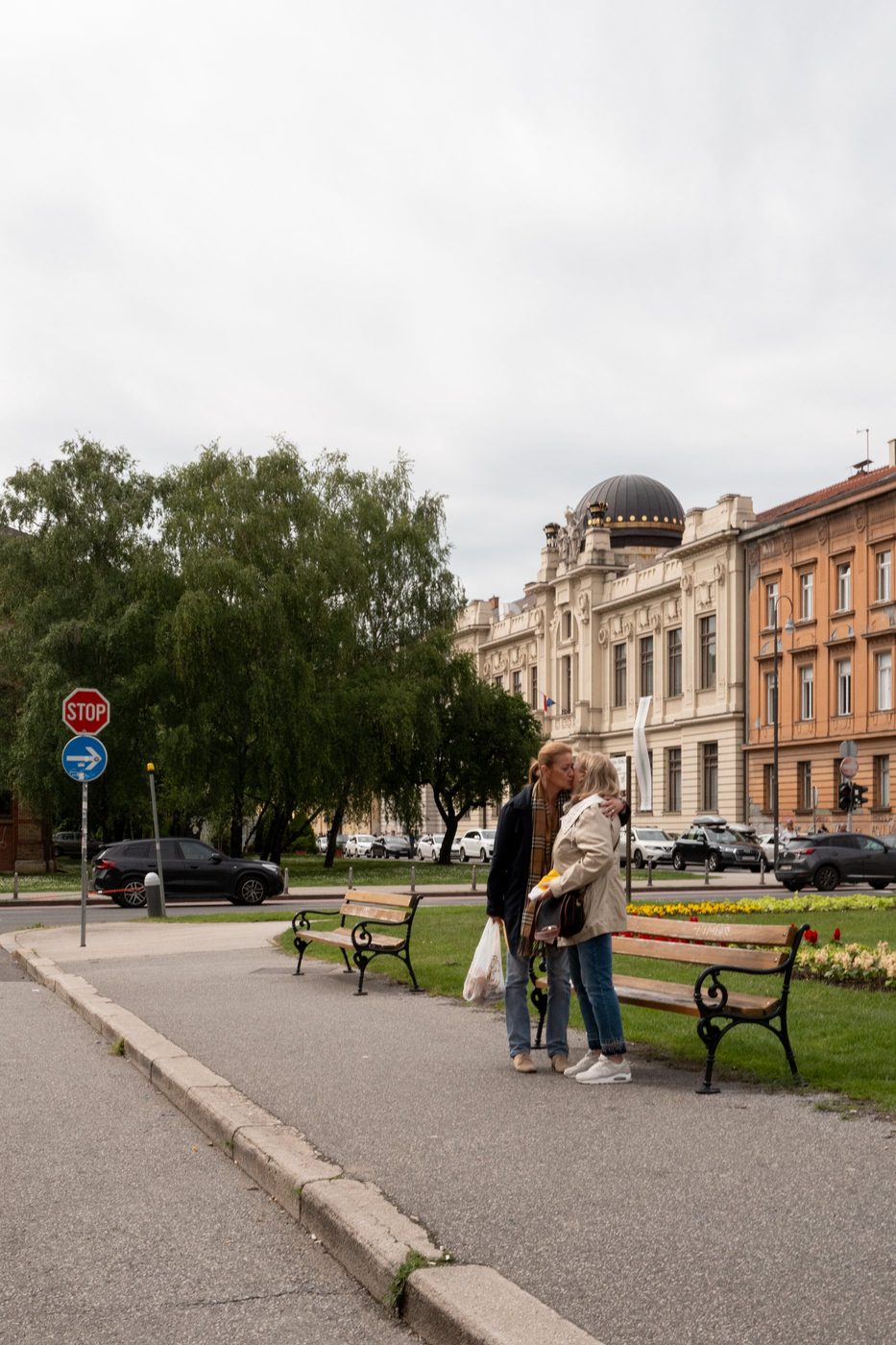 A couple kissing on a bench facing a domed building, Zagreb