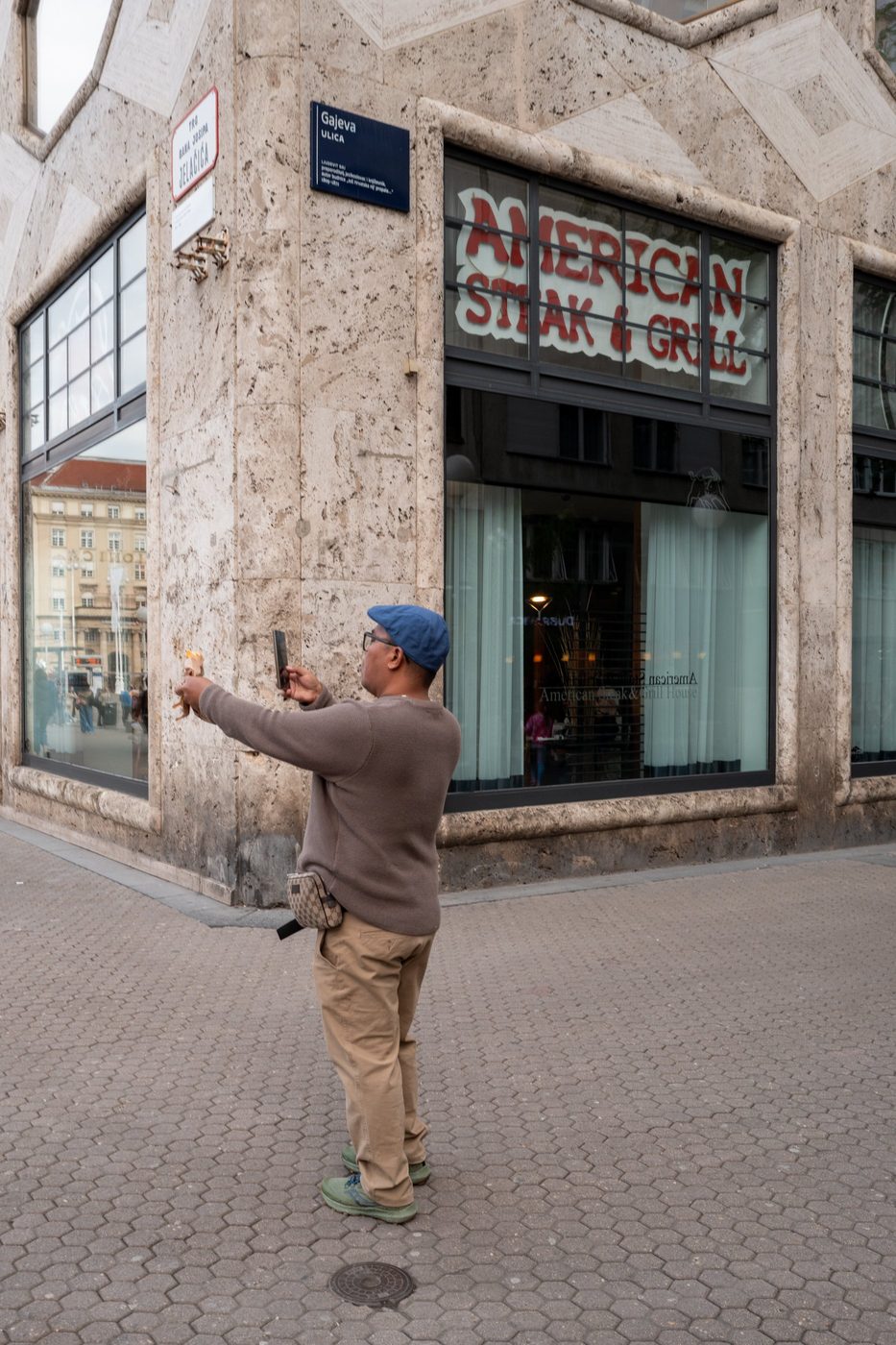 A tourist photographing a street sign at the corner of a building, Zagreb
