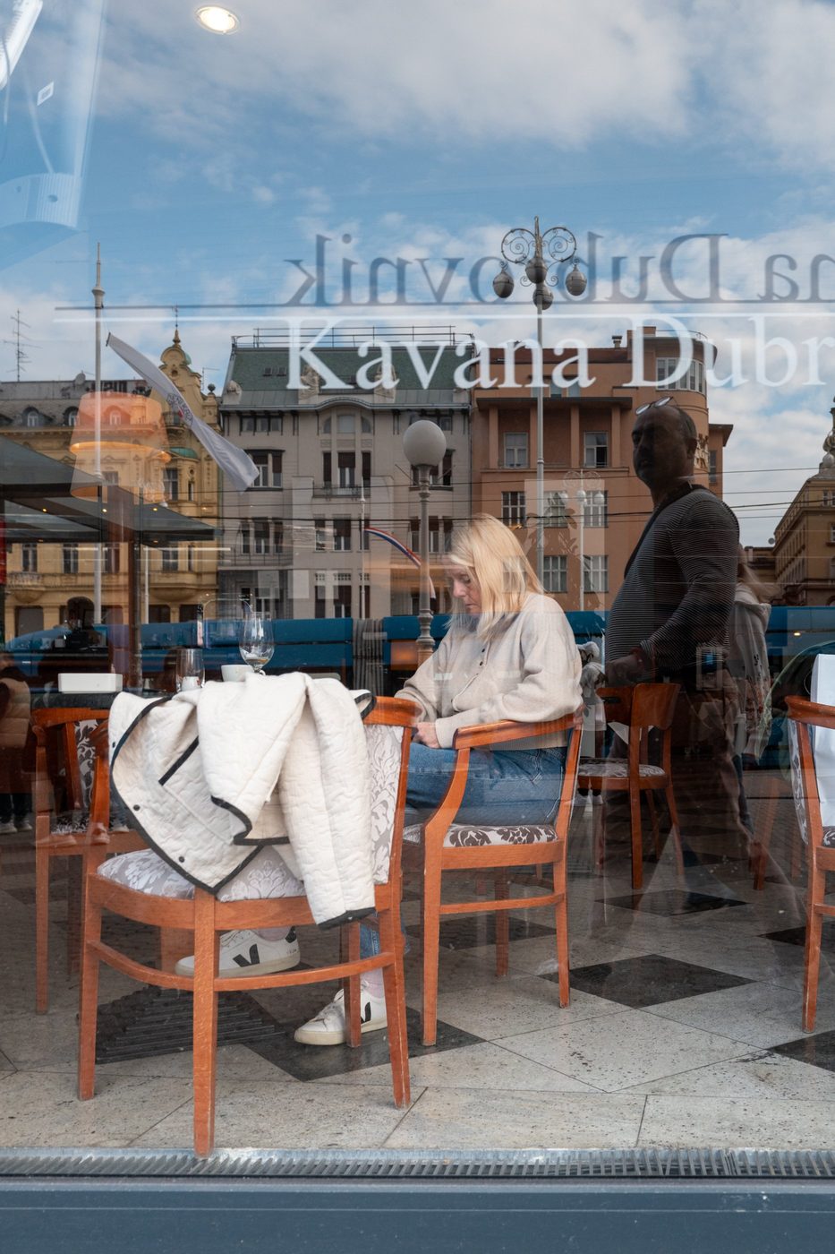 Reflection of the Kavana Dubrovnik café in a shop window, seated silhouettes, Zagreb